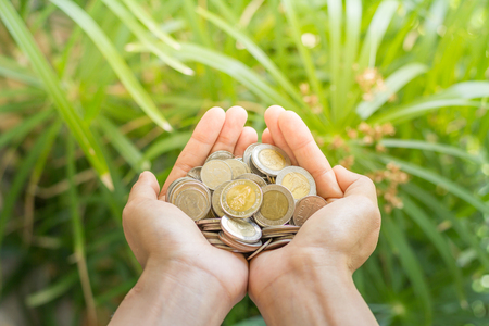 coins in the hands nature background.  save money concept.の写真素材