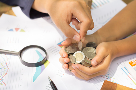 A hand adding a coin in a handful of coins. Money saving ideasの写真素材