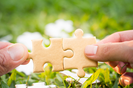 two hands trying to connect couple puzzle piece, symbol of association and connection. business strategy.の写真素材