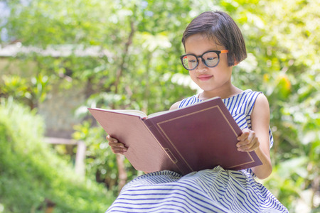 A girl sitting on a rock reading a book.,natural background,educational and Scientific Conceptsの写真素材