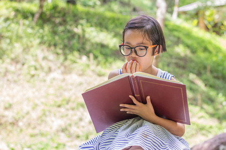 Children sit on rock eating apples and reading, educational and Scientific Conceptsの写真素材