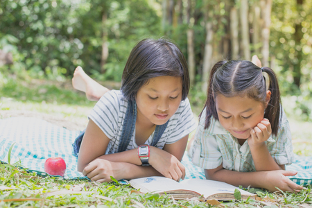Two children are reading a book,natural background,educational and Scientific Conceptsの写真素材