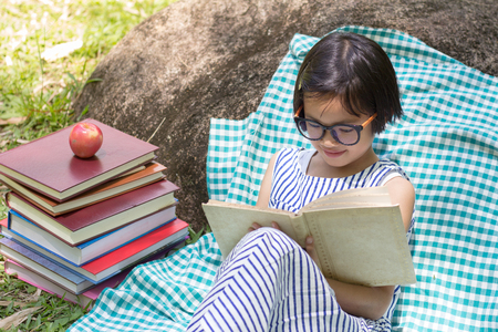 Children read the book next to the rocks, in the midst of nature,natural background,educational and Scientific Conceptsの写真素材
