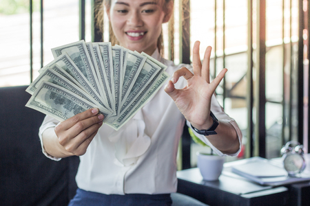 Businesswoman holding dollar currency notes in the officeの写真素材