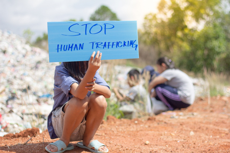 sitting child holding a sign, anti-trafficking, stopping violent acts against children, stopping child labor.の写真素材