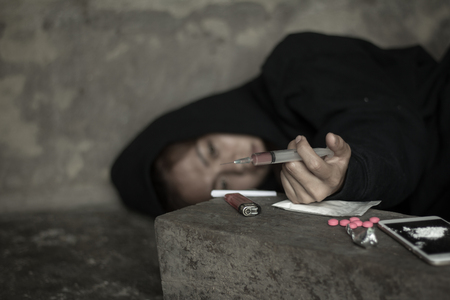 The woman holding the syringe and overdose , The concept of crime and drug addiction. 26 June, International Day Against Drug Abuse and Illicit Traffickingの写真素材