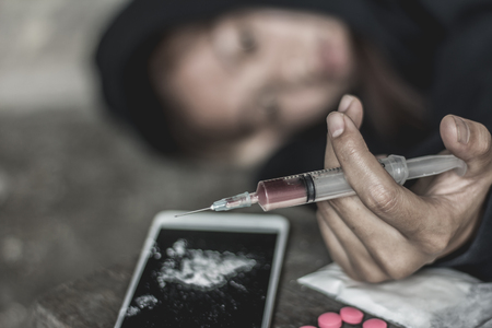 The woman holding the syringe and overdose , The concept of crime and drug addiction. 26 June, International Day Against Drug Abuse and Illicit Traffickingの写真素材