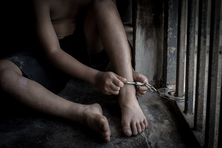 The child is trapped in an iron cage and locked with a shackle,Victims of human trafficking,Violence against children, International Anti-Trafficking Dayの写真素材