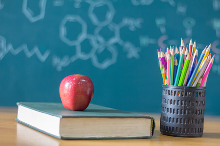 Composition of stationery ,books and an red apple on the desk,The background is blackboard, educational conceptsの写真素材