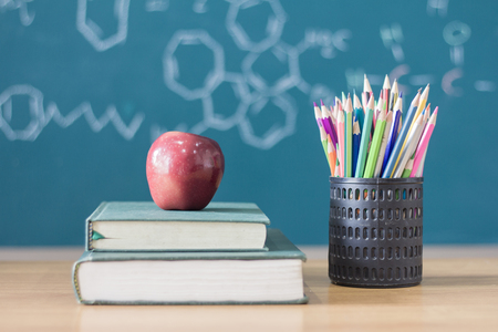 Composition of stationery ,books and an red apple on the desk,The background is blackboard, educational conceptsの写真素材