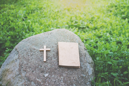 The cross and the bible is on the rock,Green background, Worship, sins and prayer.の写真素材