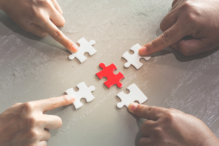 Hands of diverse people assembling jigsaw puzzle,  help support in teamwork to find common solution concept, top close up viewの写真素材