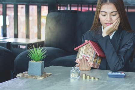 Woman holding house figure in another, The idea of saving money to buy a home.の写真素材