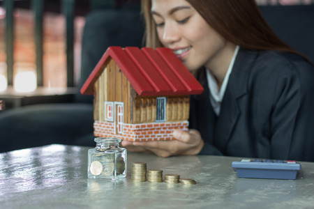Woman holding house figure in another, The idea of saving money to buy a home.の写真素材
