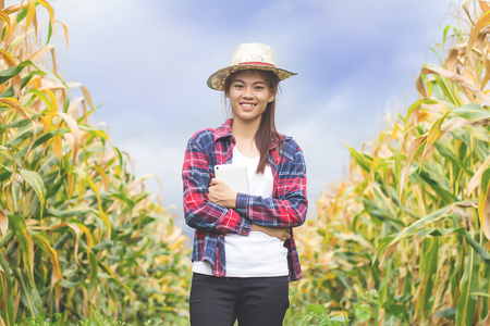A young and beautiful farmer happily smiles in his corn garden.の写真素材