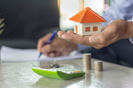 Businessman signs contract behind home architectural modelの写真素材