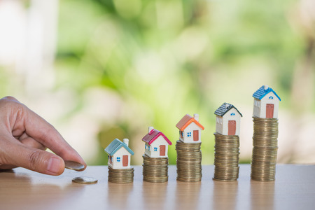 Hand putting money coin stack with small house, purchase of habitation, buy a house, Property...