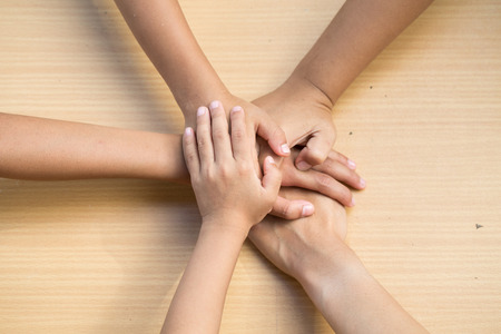 Close up top view of young people putting their hands together. Friends with stack of hands showing...
