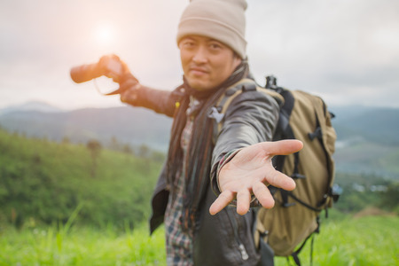 Tourist with backpack on  mountain slope with raised hands over, The valley is covered with  fog and has a beautiful sunrise. Beauty of nature, tourism and traveling concept.の写真素材