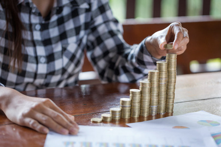 women hand put money coins to stack of coins. Business Growth concept.