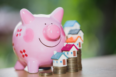 Real estate sale, home savings, piggy bank, coins and a house, loans market concept. Housing industry mortgage plan and residential tax saving strategy.の写真素材