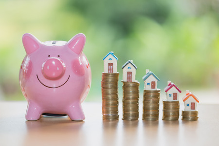Real estate sale, home savings, piggy bank, coins and a house, loans market concept. Housing industry mortgage plan and residential tax saving strategy.の写真素材