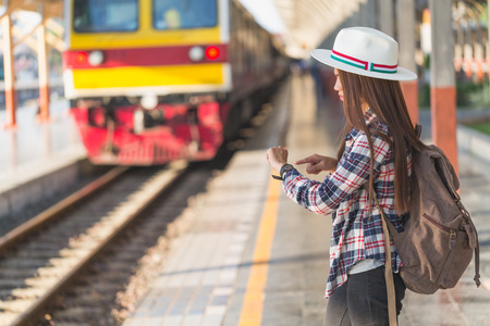 Beautiful young asian woman traveler looking clock  with brown bag ,Waiting for train at train station, Chinese tourists, Travel and vacation concept.の写真素材