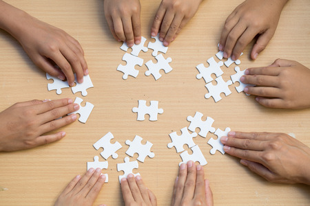 Hands of diverse people assembling jigsaw puzzle, Youth team put pieces together searching for right match, help support in teamwork to find common solution concept, top close up viewの写真素材