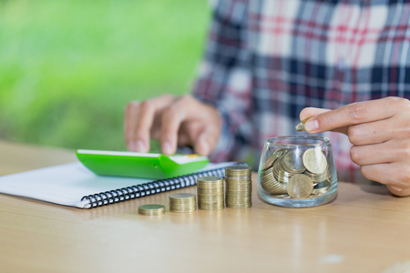 Business accounting with saving money with hand putting coins in jug glass, Businessman Writing Financial Accounting, concept financialの写真素材