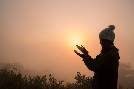 Silhouette of young  human hands open palm up worship and praying to god  at sunrise, Christian Religion concept background.の写真素材