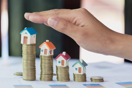 Hand protection, house model on top of stack of money as growth of mortgage credit, Concept of property management. Invesment and Risk Management.の写真素材