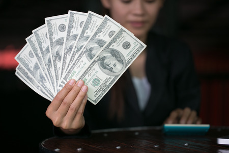 Business woman displaying a spread of cash over,  spending money or profit from business operations...