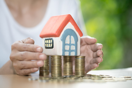 Hand protection, house model on top of stack of money as growth of mortgage credit, Concept of property management. Invesment and Risk Management.の写真素材