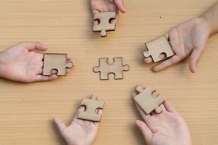 Hands of diverse people assembling jigsaw puzzle, Youth team put pieces together searching for right match, help support in teamwork to find common solution concept, top close up viewの写真素材
