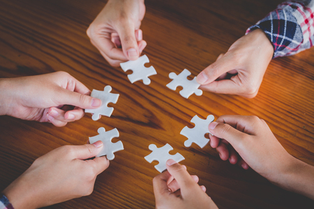 Hands of diverse people assembling jigsaw puzzle, Youth team put pieces together searching for right match, help support in teamwork to find common solution concept, top close up viewの写真素材