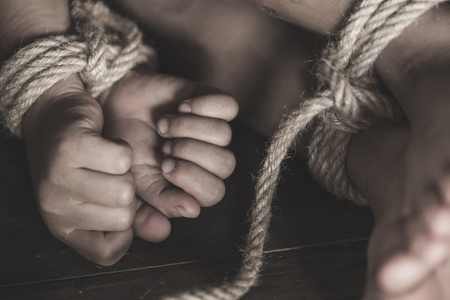 Victim boy with hands tied up with rope in emotional stress and pain,  kidnapped, abused, hostage,  afraid, restricted, trapped,  struggle,  Stop violence against children and trafficking Concept.の写真素材