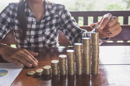 women hand put money coins to stack of coins. Business Growth concept.