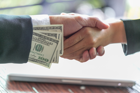 Hand receiving money, US dollars, from business man, Businessman giving money to his partner while making contract - bribery and corruption conceptsの写真素材