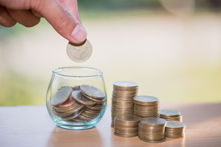 Woman hand putting coinIn the glass jar. Saving money wealth and financial concept.の写真素材