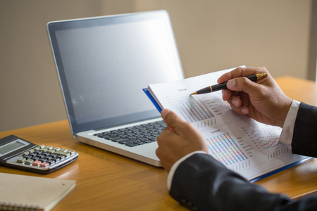 close up of businessman hand working on laptop computer with financial business graph information,  analyzing investment charts.の写真素材