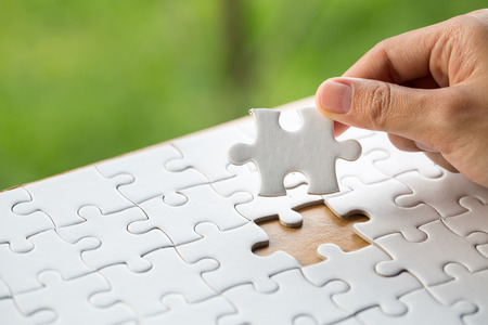 Hand put the last piece of jigsaw puzzle to complete the mission, Business solutions, success and strategy conceptの写真素材