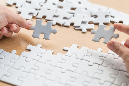 Closeup hand of connecting jigsaw puzzle to complete the mission with sunlight effect, Business solutions, success and strategy conceptの写真素材