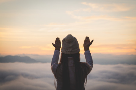 Young christian woman  hands open palm up worship and praying to god  at sunrise, Christian Religion concept background.の写真素材
