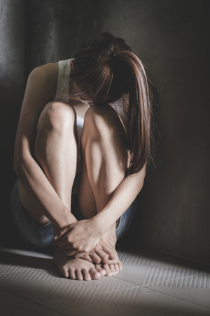 The depressed teen sat on the floor, stressed sad young woman having mental problems,Domestic Violence and Traffickingの写真素材