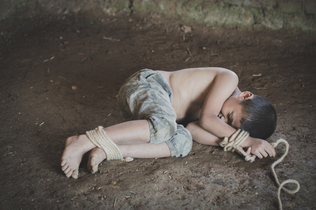 Victim boy with hands tied up with rope in emotional stress and pain,  kidnapped, abused, hostage,  afraid, restricted, trapped, pitiable,  struggle,  Stop violence against children and trafficking Concept.の写真素材