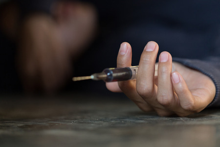 Young woman  hand holding a syringe and drug overdose,The concept of crime and drug addiction. 26 June, International Day Against Drug abuse.の写真素材