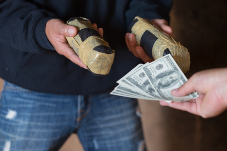 Hand of addict man with money buying dose of cocaine or heroine, close up of addict buying dose from drug dealer, drug trafficking, crime, addiction and sale concept,の写真素材