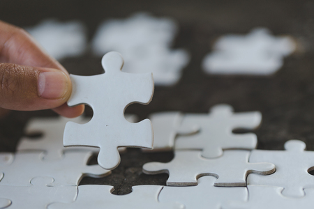 The woman hand holds a wooden jigsaw, solutions and strategy Concept.の写真素材