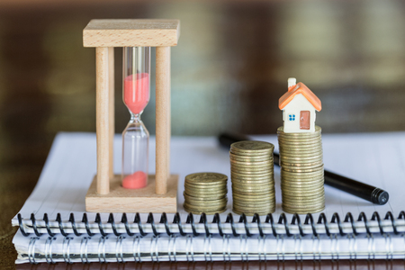Mini house on stack of coins,Money and house,  Mortgage, Savings money for buy house and loan to business investment for real estate concept. Invesment and Risk Management, hourglass.の写真素材