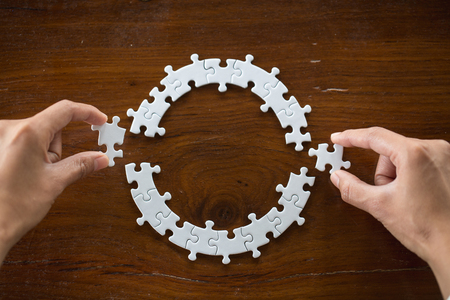 Closeup hand of connecting jigsaw puzzle to complete the mission with sunlight effect, Business solutions, success and strategy conceptの写真素材